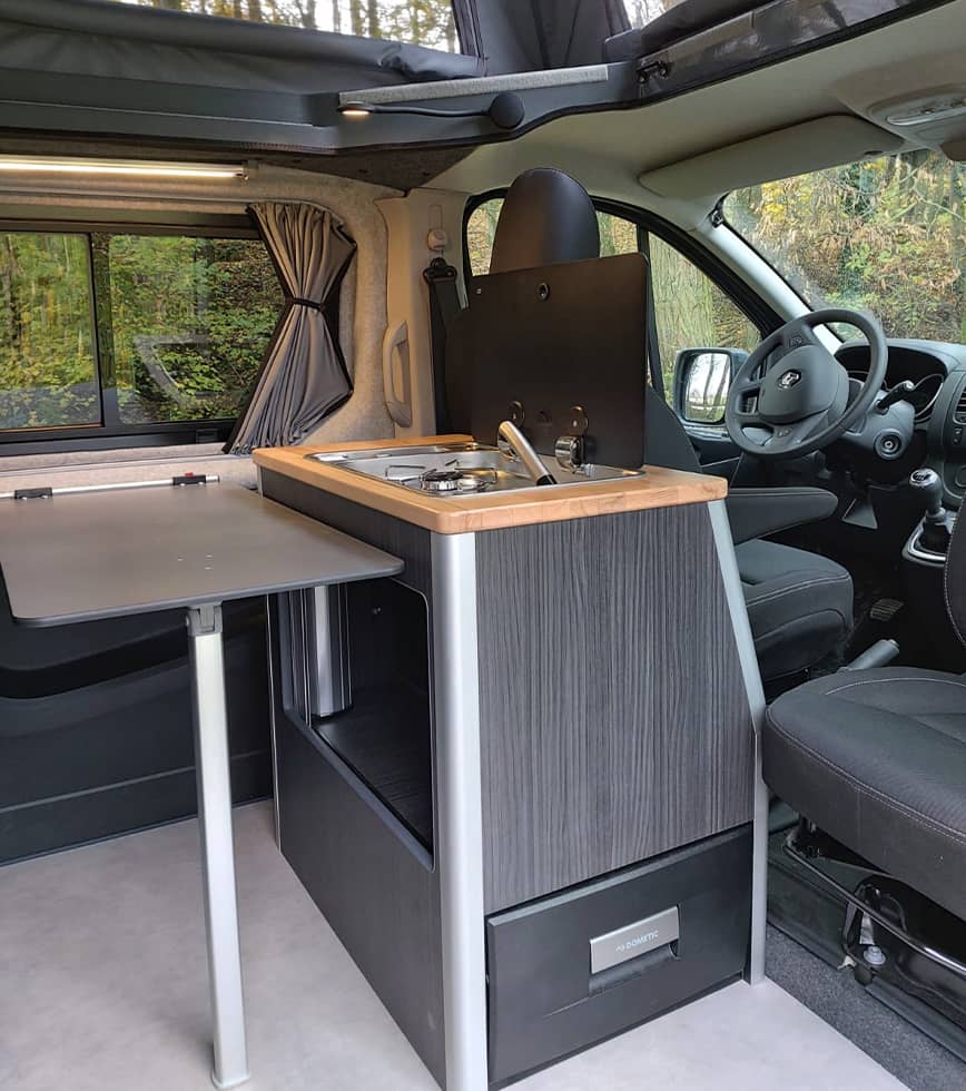 Cuisine intégrée dans un van Ovan Liberty, avec une table escamotable, un espace de cuisson moderne et un toit relevable