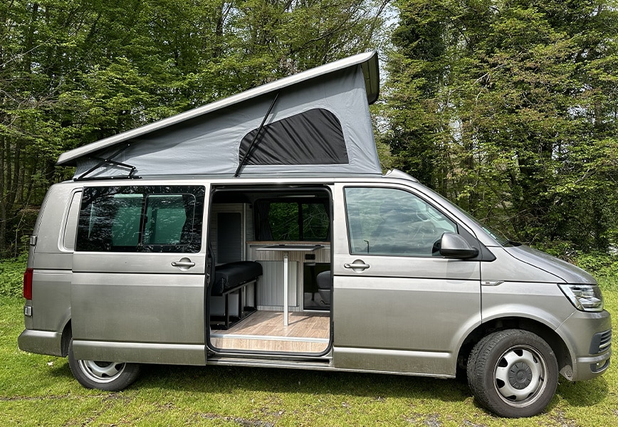 Van aménagé avec toit relevable offrant un espace intérieur optimisé et confortable pour le camping en pleine nature