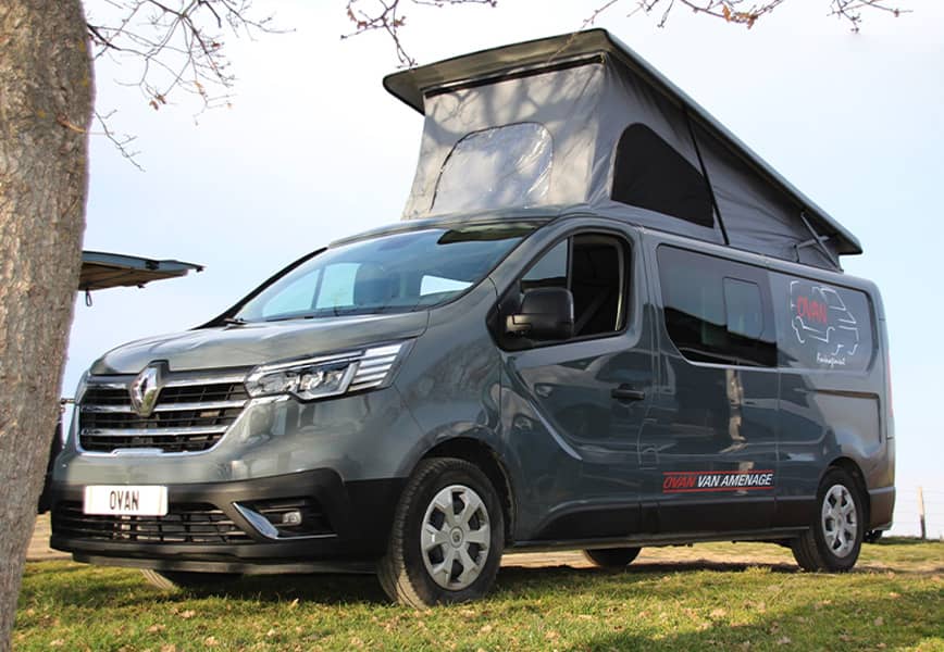 Van Renault gris aménagé par Ovan avec toit relevable ouvert, stationné en extérieur