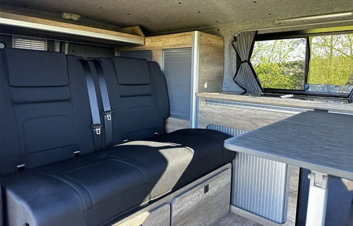 Aménagement intérieur d'un van Ovan avec banquette convertible et espace de rangement intégré