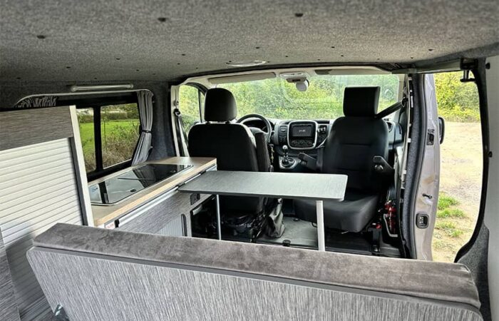 Vue intérieure d'un van aménagé par Ovan avec table, banquette et espace de conduite